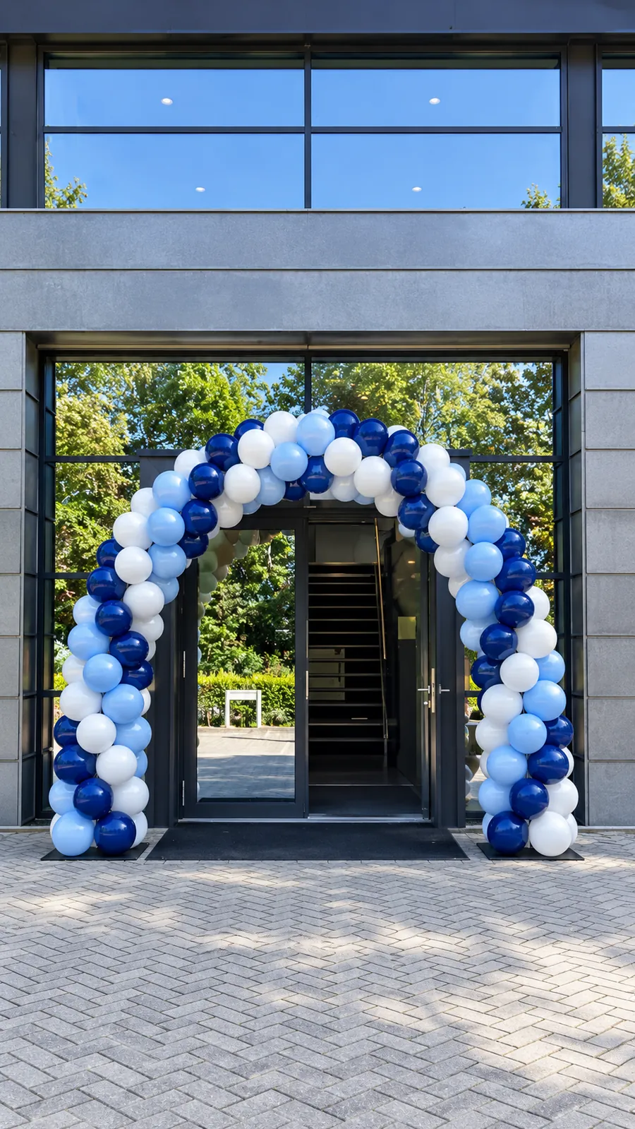 Ballonnenboog in blauw, wit en lichtblauw over de ingang van een kantoorgebouw